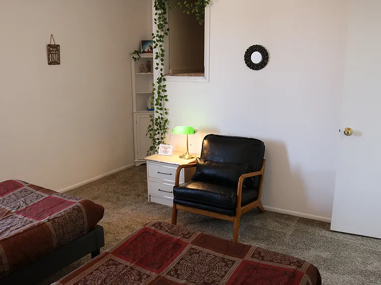 Second bedroom, another angle showing leather chair, cubby hole storage, closet.