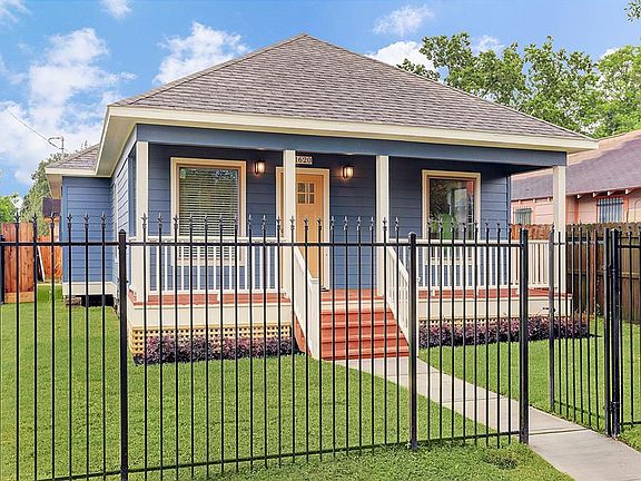Charming fleur-de-lis wrought iron front yard with pedestrian gate.