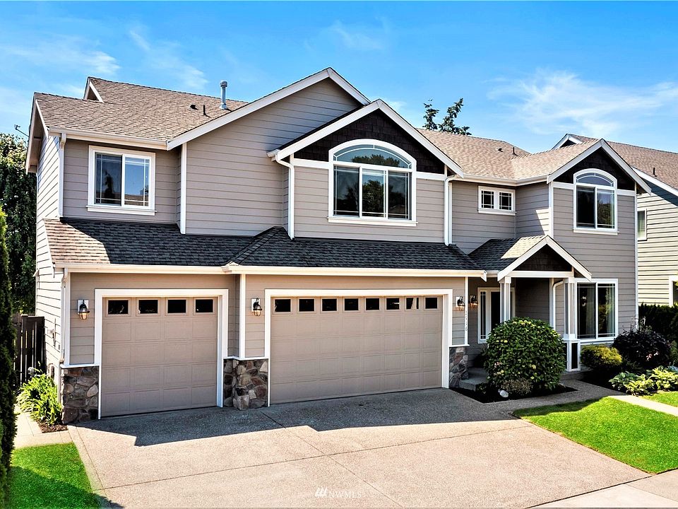 Strikingly crisp front view showing off vaulted bedrooms upstairs, mature landscaping & 3 car garage >