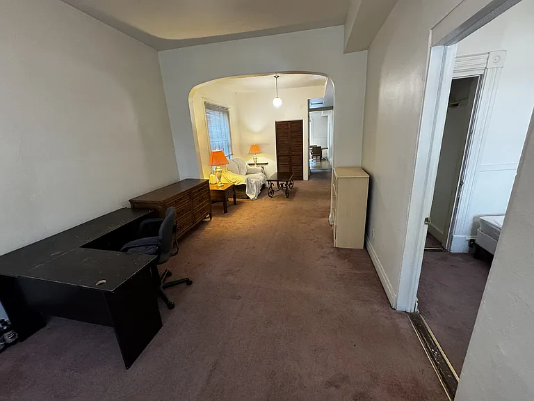 Another view of the front living room in the foreground and the middle living space in the background. Tables, lamps and sofa are included.