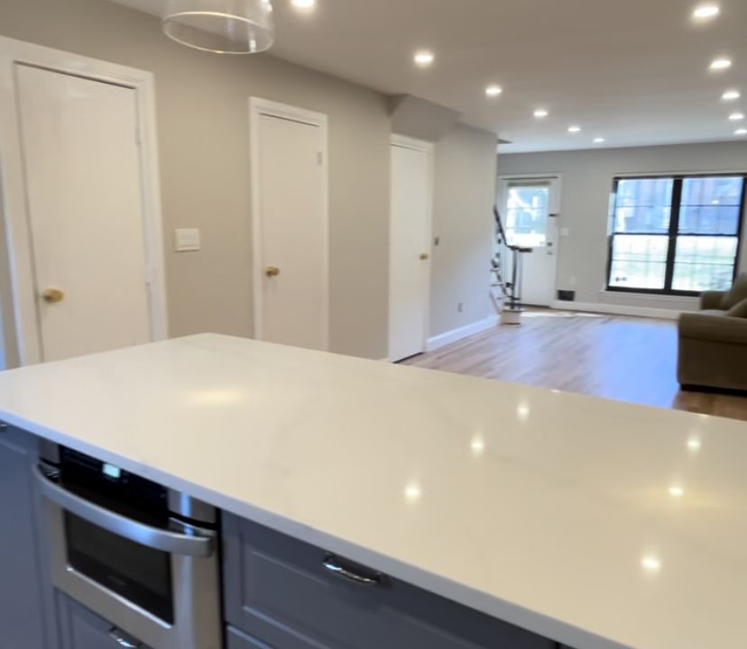 View of the kitchen and living room from the back door. Left door is a utility/coat closet, middle door is a half bath, right door goes to basement. Note plenty of recessed LED lighting which is on dimmers.