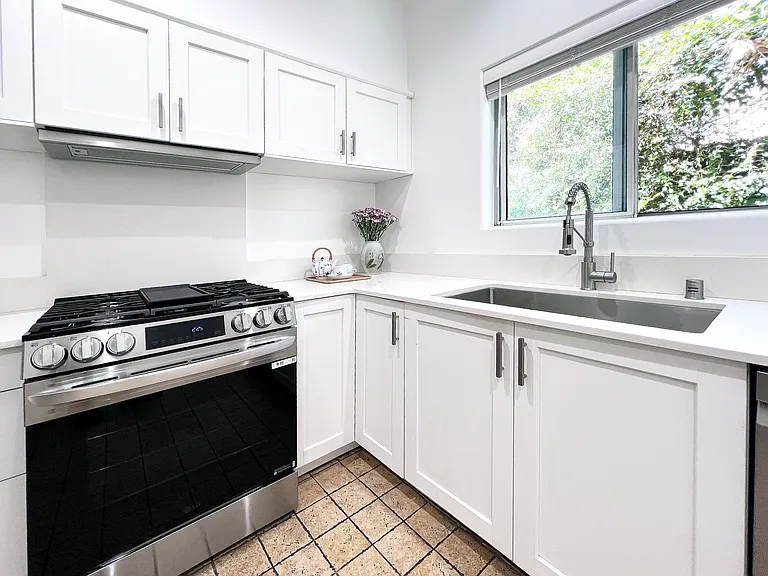 Fully renovated kitchen featuring a premium LG gas stove, a chef-level sink and faucet, and a peaceful window view over brand-new quartz countertops.