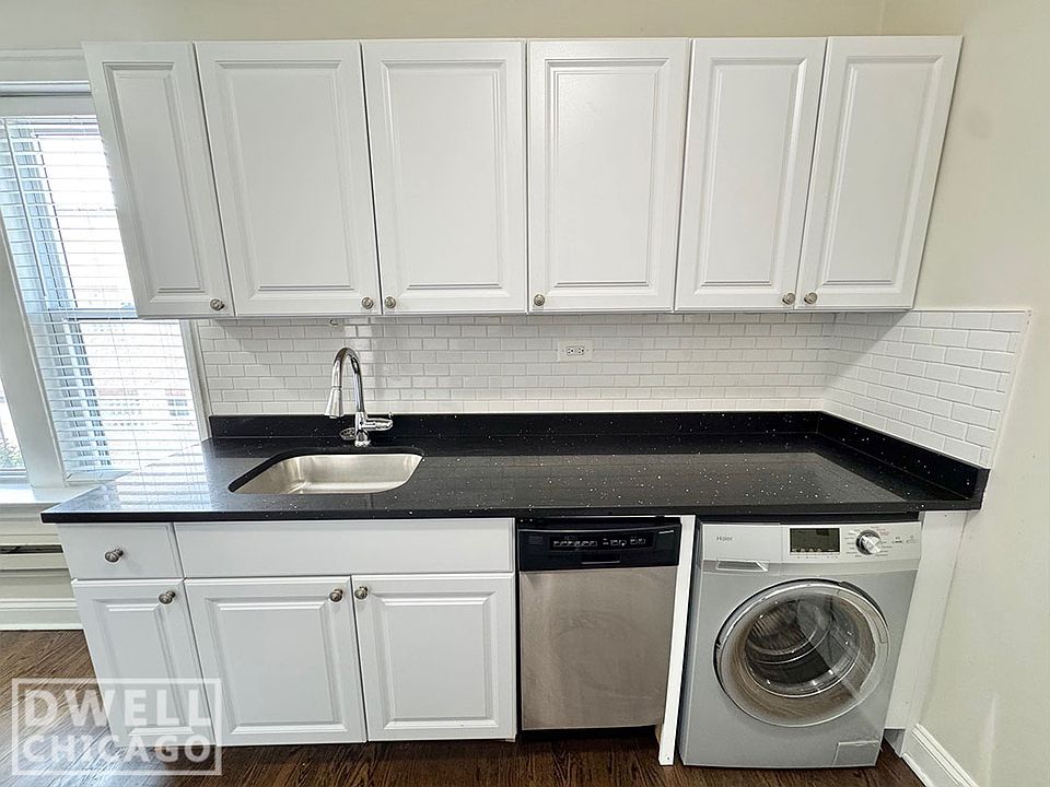 Kitchen with large quartz countertop, tons of cabinet space, dishwasher, and washer/dryer.