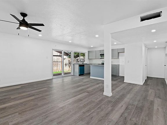 Unfurnished living room featuring ceiling fan and dark hardwood / wood-style floors