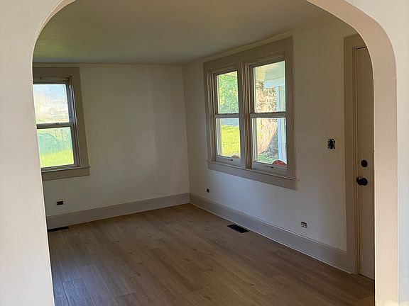 View of living room from dining room ft. new floors & paint colors (Walls: SW Timeless White & Trim: SW Bungalow Beige)