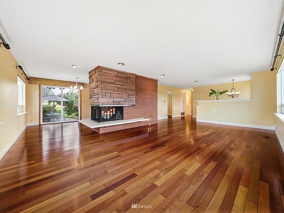 The family room flows around the stone centrally located woodburning fireplace into the dining area. White baseboards & trim neutral colored walls & hardwood floors are timeless. 