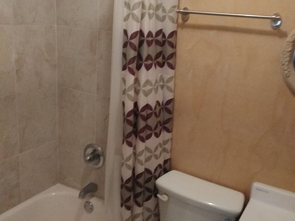 Primary bathroom with but and shower combination and tiled floor.