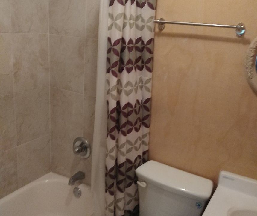 Primary bathroom with but and shower combination and tiled floor.