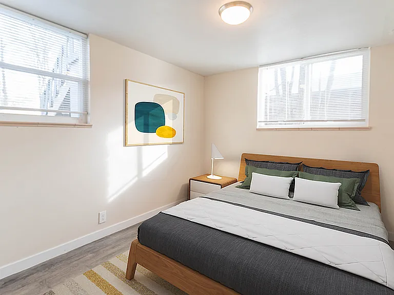 Bright and modern bedroom with stylish decor, featuring a cozy bed, minimalist artwork, and natural light streaming through large windows.