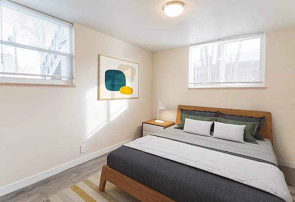 Bright and modern bedroom with stylish decor, featuring a cozy bed, minimalist artwork, and natural light streaming through large windows.