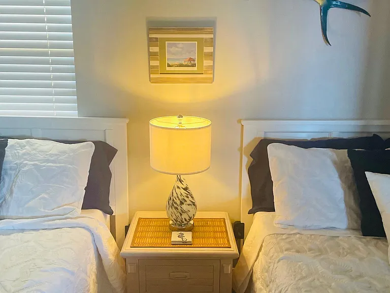 Guest bedroom with a lamp that lights up at base with just a slight touch . You can also plug your phones into the side of this beautiful lamp .