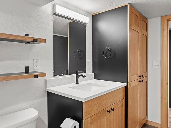 Bathroom with floating shelves, custom white oak cabinets with linen pantry, and tiled shower