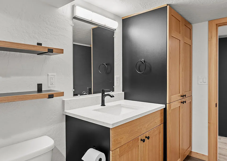 Bathroom with floating shelves, custom white oak cabinets with linen pantry, and tiled shower