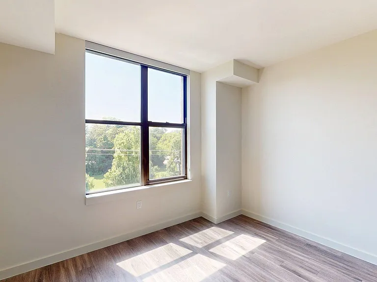 Spacious apartment bedroom with wood style floor.