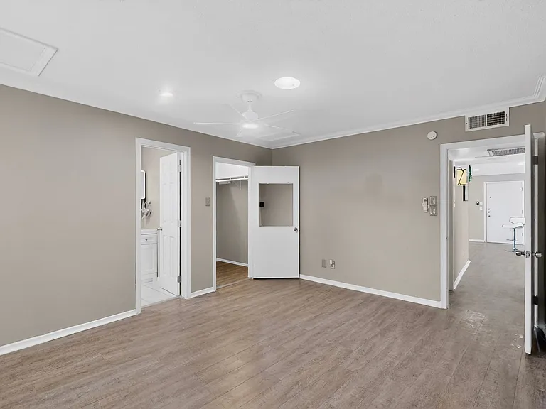 A spacious primary bedroom with wooden floors, a ceiling fan, a walk-in closet and an en suite bath; designed for functionality and comfort.