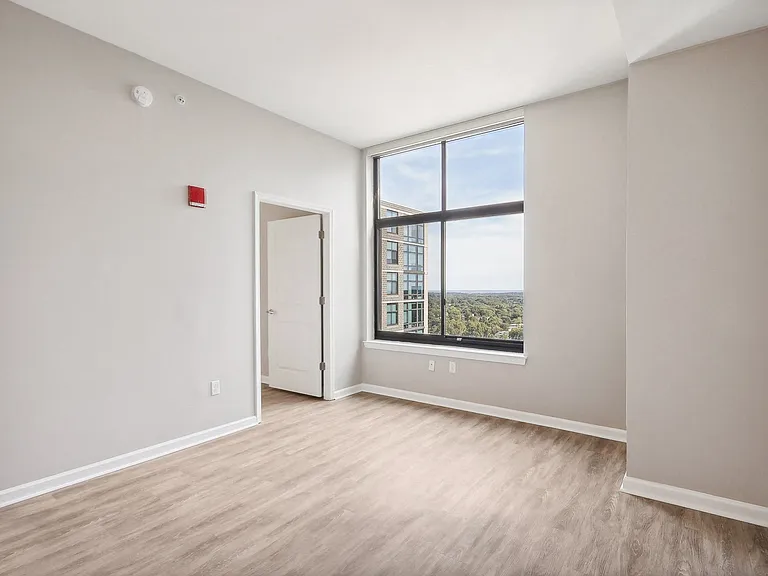 an empty living room with a large window and wood flooring