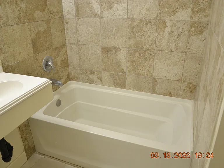 Deep soaking tub with porcelain tile enclosure.
