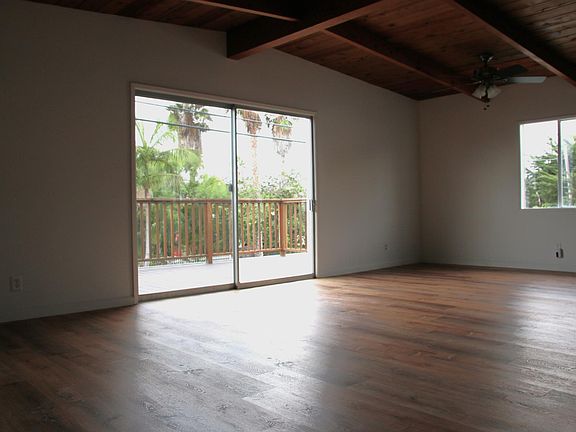 Living room/dining room with exposed wood beam ceilings and new hardwood-like floors.