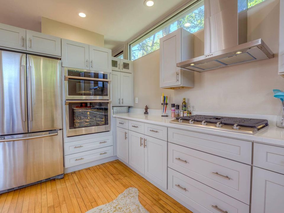 Recently renovated kitchen with french door refrigerator, double oven featuring a smart oven/microwave combination, gas range and quartz counters