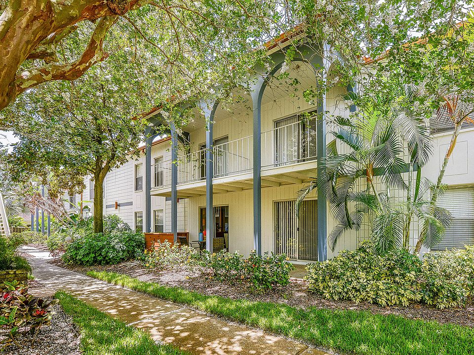 Charming apartment exterior with lush landscaping, featuring a bright two-story design and inviting balconies.