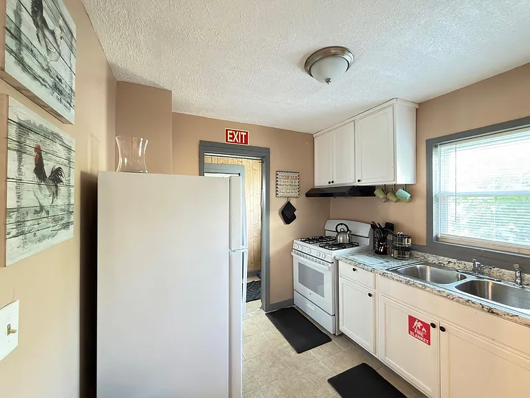 Efficient kitchen with ample cabinetry, double-basin sink, and full-size range, plus a window over the counter.