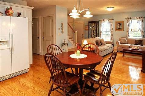 Another view of the dining area looking into the living room showing front door and stairs to second level.