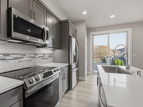 Modern updated kitchen with stainless steel appliances, quartz countertops, tiled backsplash and French door refrigerator