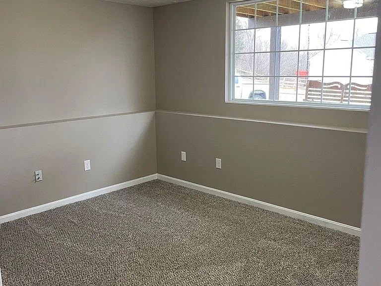 Rear room on lower level. Still very light and bright! New carpet, paint and light fixture.