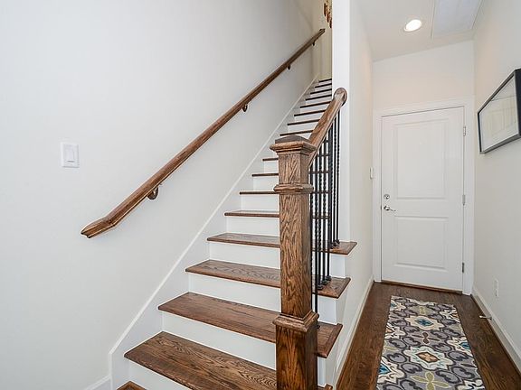 Staircase leading up to main living area and kitchen. Door leads to garage. This first floor also has one of two secondary bedrooms.
