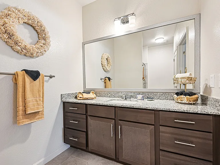 Sleek and modern bathroom with elegant granite countertop, stylish dark wood cabinetry, and luxurious decor.
