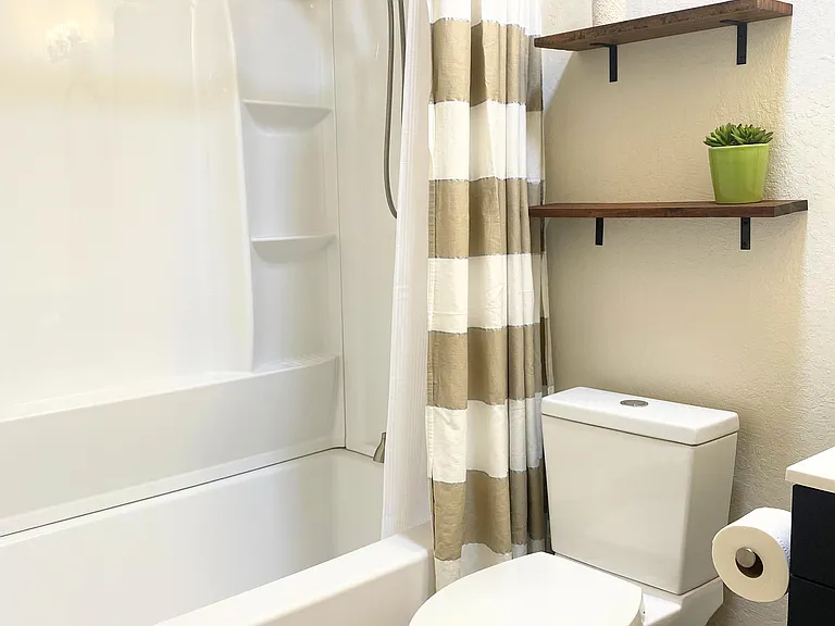 Hallway bathroom features a convenient tub-shower combo perfect for a quick refresh or a relaxing soak. It's all you need for a comfortable clean-up!