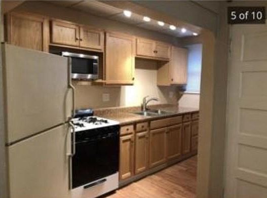 Bright galley kitchen with full refrigerator, gas stove and microwave.