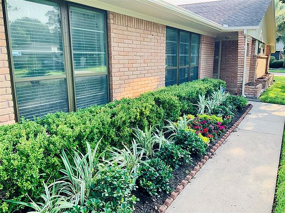 The sidewalk enters from the driveway and is bordered by beautiful landscaping