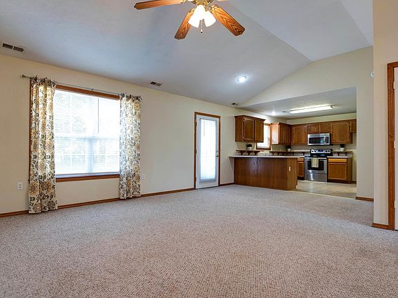 Living room with vaulted ceiling. Ceiling fan to keep the breeze going.