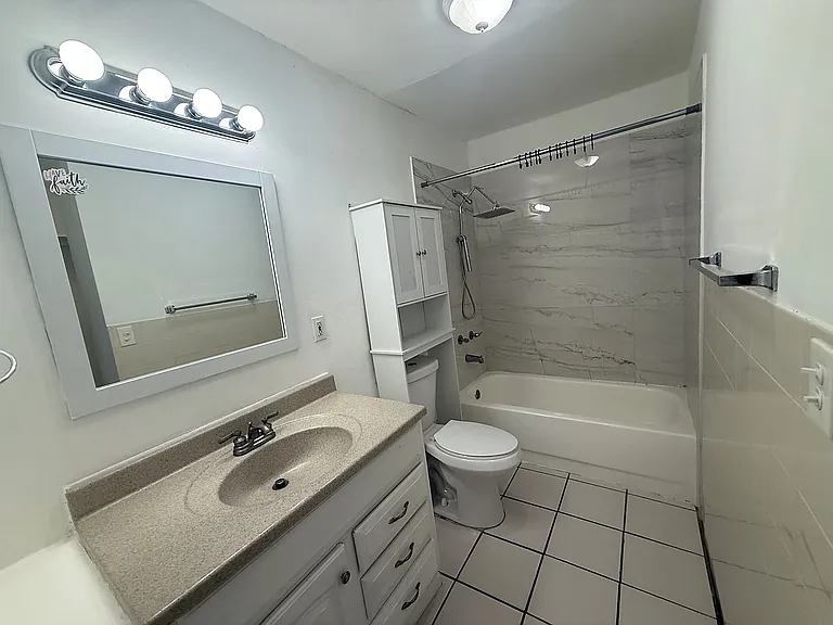 Full bathroom with vanity, tub/shower combination, tiled shower surround and additional storage.