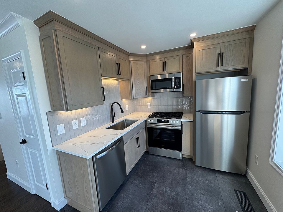 Brand new kitchen with quartz counters, large sink, under cabinet lighting and new appliances.