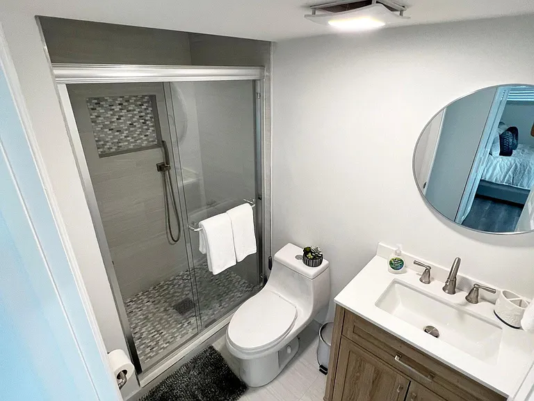 Clean bathroom with cabinet, mirror, toilet, shower, and essential toiletries.