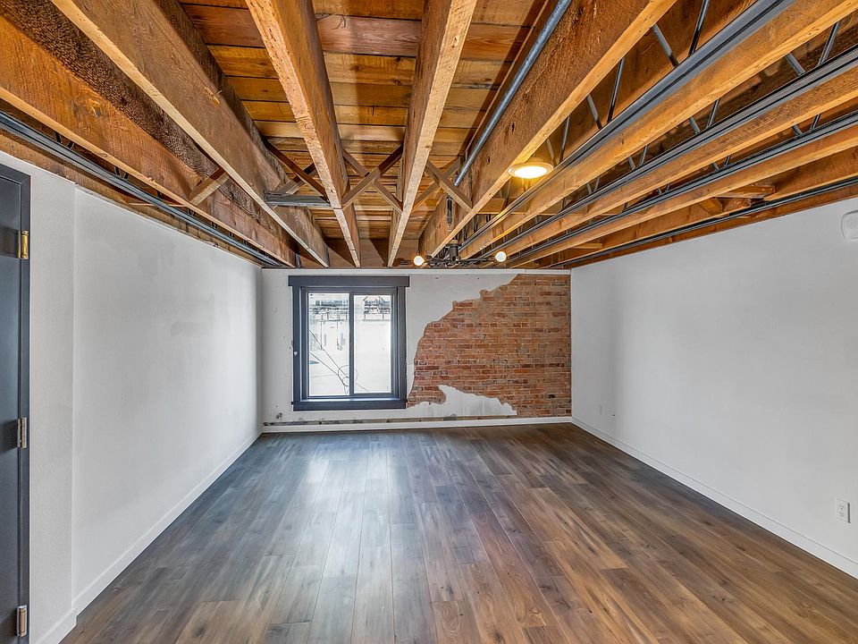 Living room open to the kitchen with exposed brick and plaster and open rafter ceiling
