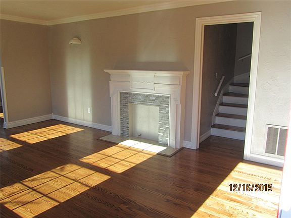 Living area with beautiful hardwood floors, crown molding, and refinished stairs to second level.