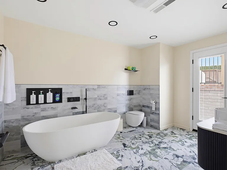 Brand-new primary bathroom with a new toilet and bathtub (Pic 1)