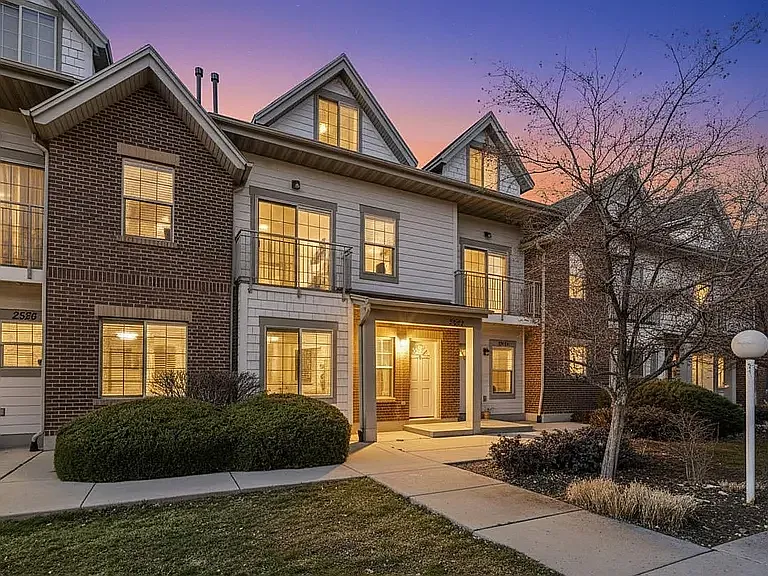 Classic brick and siding exterior with a covered front entry, second-floor balcony, and manicured landscaping.