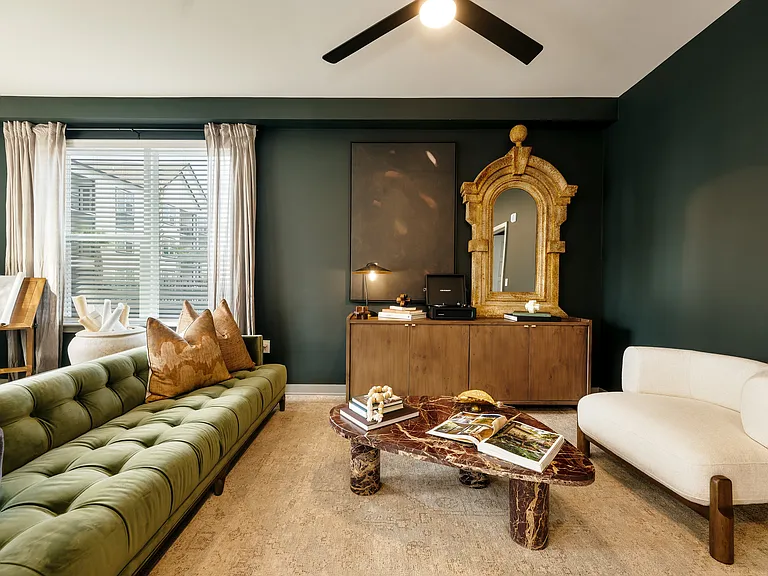 Stylish apartment living room with wood-inspired flooring, oversized windows, ceiling fan, and curated designer finishes.