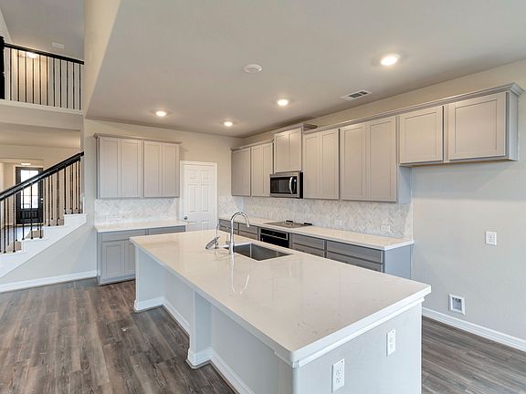 The kitchen features light cabinetry, quartz countertops and a modern backsplash.