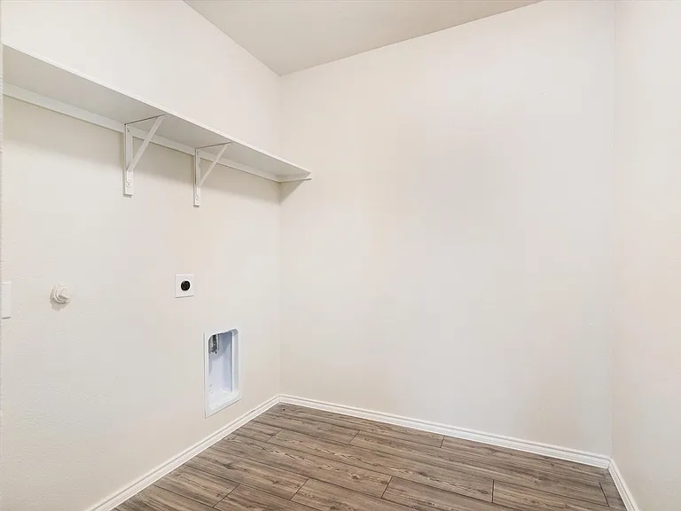 Utility area featuring wood-finish flooring, white baseboards, and light-colored walls