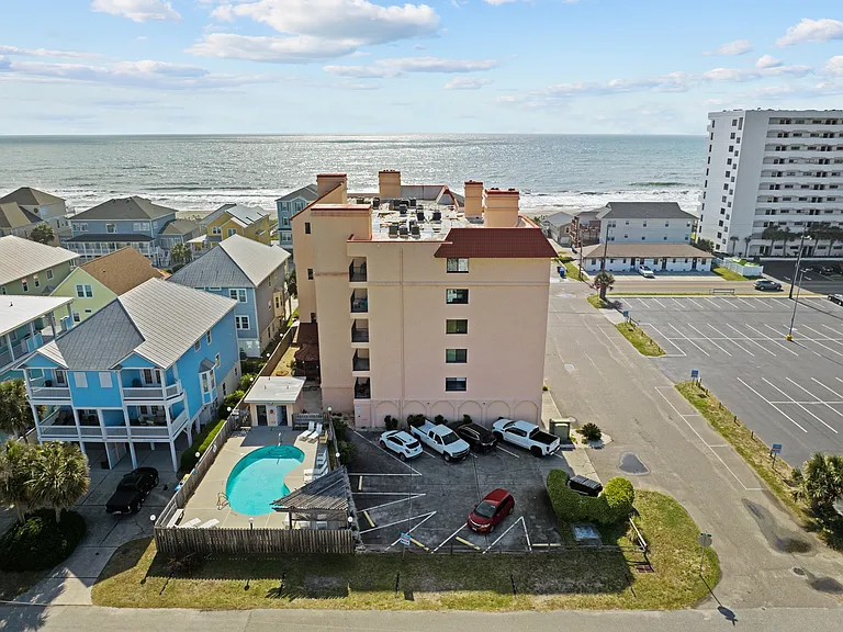 View of building (some parking, pool, trash bins). Additional parking around the building.
