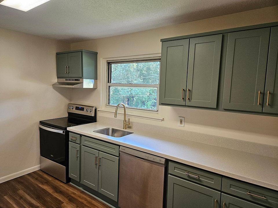Updated kitchen with green shaker cabinets, brass hardware, new appliances and Corian countertops