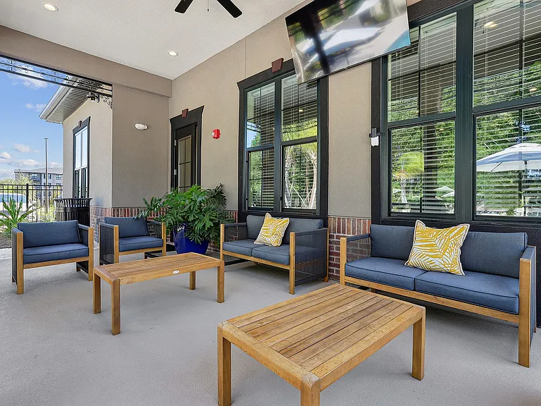 Chic covered patio with stylish outdoor seating, ceiling fan, and lush greenery, offering a serene retreat for relaxation.