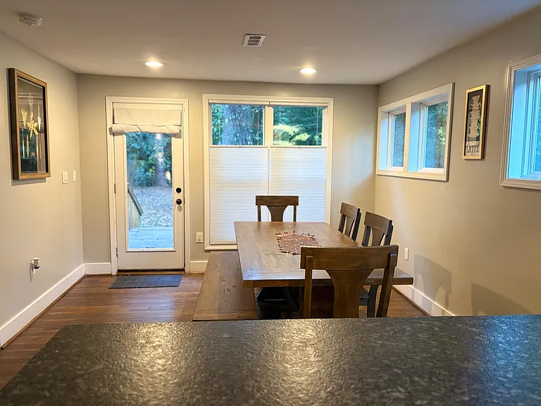 Dedicated dining area with wood table seating and large windows plus a door for easy access to the patio.