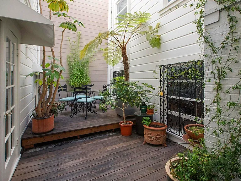 Wooden deck surrounded by a variety of potted plants and trees