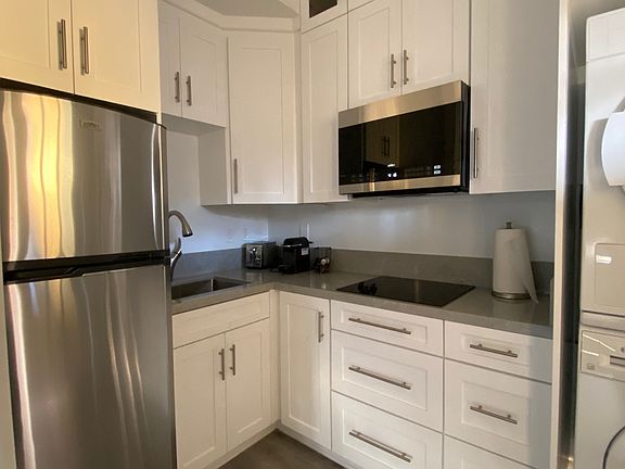Shot of the kitchen with quartz counter top and black glass cooktop cooktop along with midsize microwave